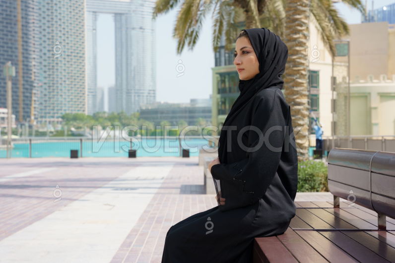  امرأة عربية مجبة ترتدي عباية سودا وتجلس على مقد باقرب من بحيرة  