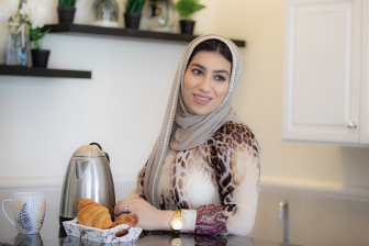امرأة عربية محجبة مبتسمة تحضر الفطور