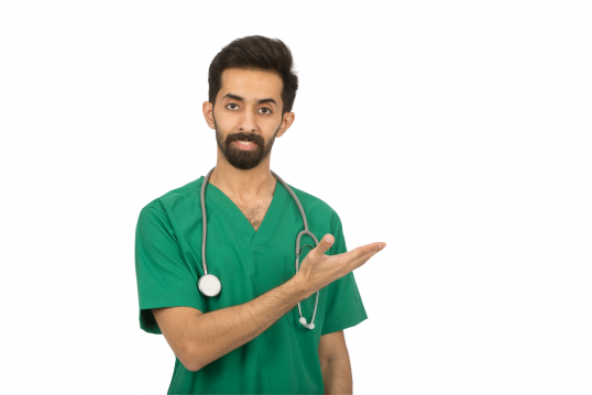 طبيب عربي سعودي مبتسم يضع السماعة الطبية حول عنقه يشير بيده إلى يساره وينظر إلى الكاميرا