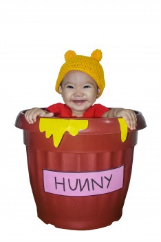 طفلة صغيره جملية تقف بسعادة داخل وعاء كبير مكتوب عليه عسل