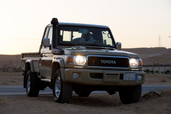 رجل سعودي يقود سيارة مارة ويوتا علي الطريق الصحراوي في وقت اغروب