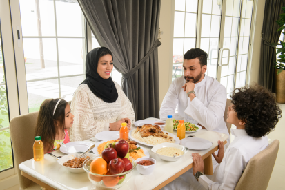 عائلة عربية سعودية تستمتع بتناول الطعام معاً في المنزل