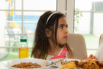 طفلة عربية سعودية تجلس على طاولة الطعام وتنظر إلى اليمين