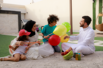 عائلة سعودية في نزهة معًا ، يلعبون بالبالونات