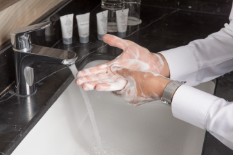 رجل عربي خليجي يرتدي ثوب أبيض يغسل يديه بالماء والصابون