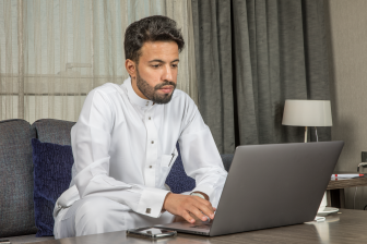 رجل عربي سعودي يعمل من المنزل باستخدام اللابتوب