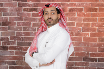 صورة جانبيه لرجل سعودي يردي ثوبً تقليديً يقف أثناء النظر لى الكاميا