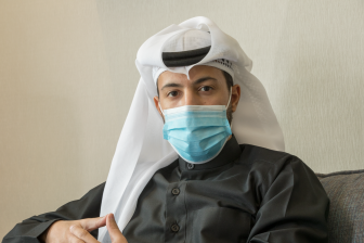رجل عربي سعودي يرتدي كمامة و ينظر إلى الكاميرا